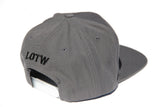 Side view of grey LOTW Gear snapback baseball hat with black embroidered logo
